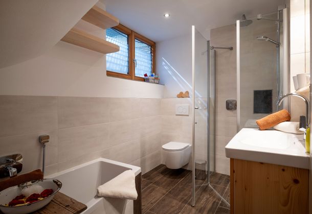 Badezimmer mit Badewanne, ebenerdiger Glasdusche, WC und Waschtisch