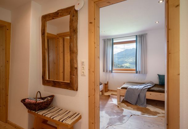 Flur mit rustikalem Holzspiegel und Blick in ein Schlafzimmer